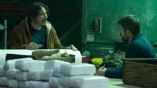 Sergio Peris-Mencheta as Gustavo and Carter Hudson as Teddy McDonald sitting in front of bags of cocaine in Snowfall season 6