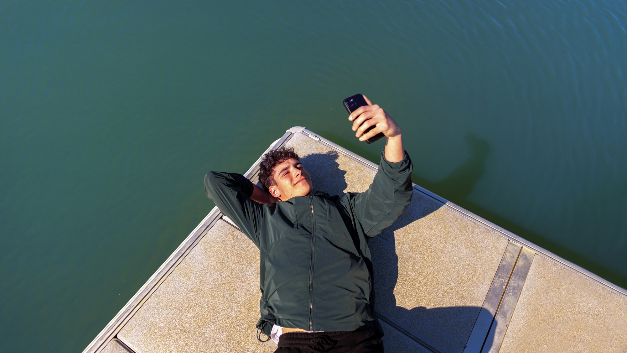 A person holding an iPhone, sat near water