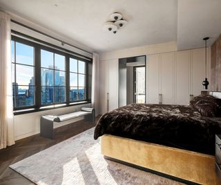 Trevor Noah's Penthouse – Bedroom with king sized bed facing a large horizontal window offering panoramic views of the city