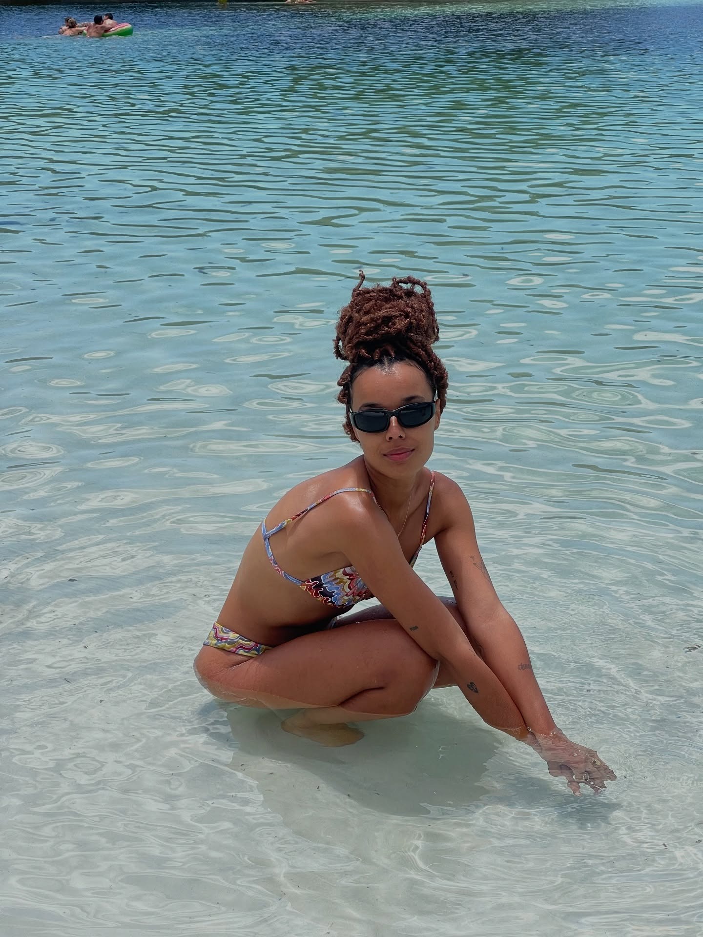 A woman wearing a loc&#039;d topknot in the water.
