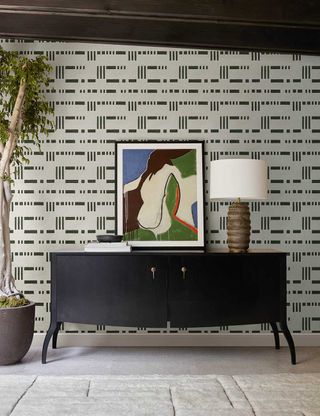 a striped wallpaper behind a black sideboard