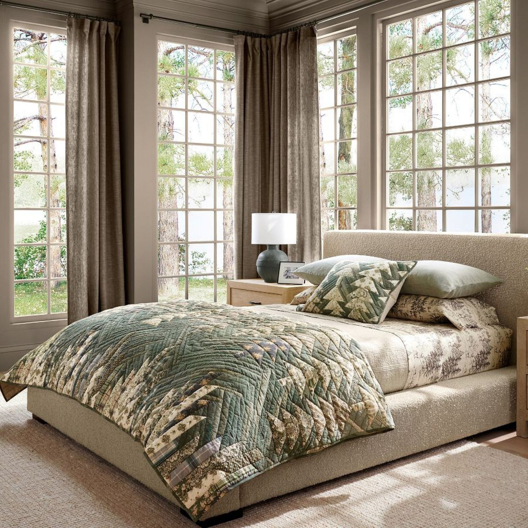 A light-filled bedroom with a beige boucle bed with a quilted patchwork bedspread and matching pillow from the Pottery Barn Christmas collection