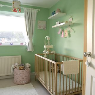 childrens room with green walls toys and wooden baby cot