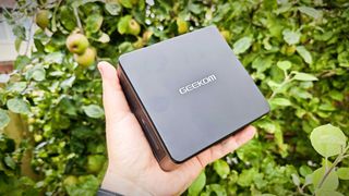A black Geekom IT15 mini PC sitting in a grassy field