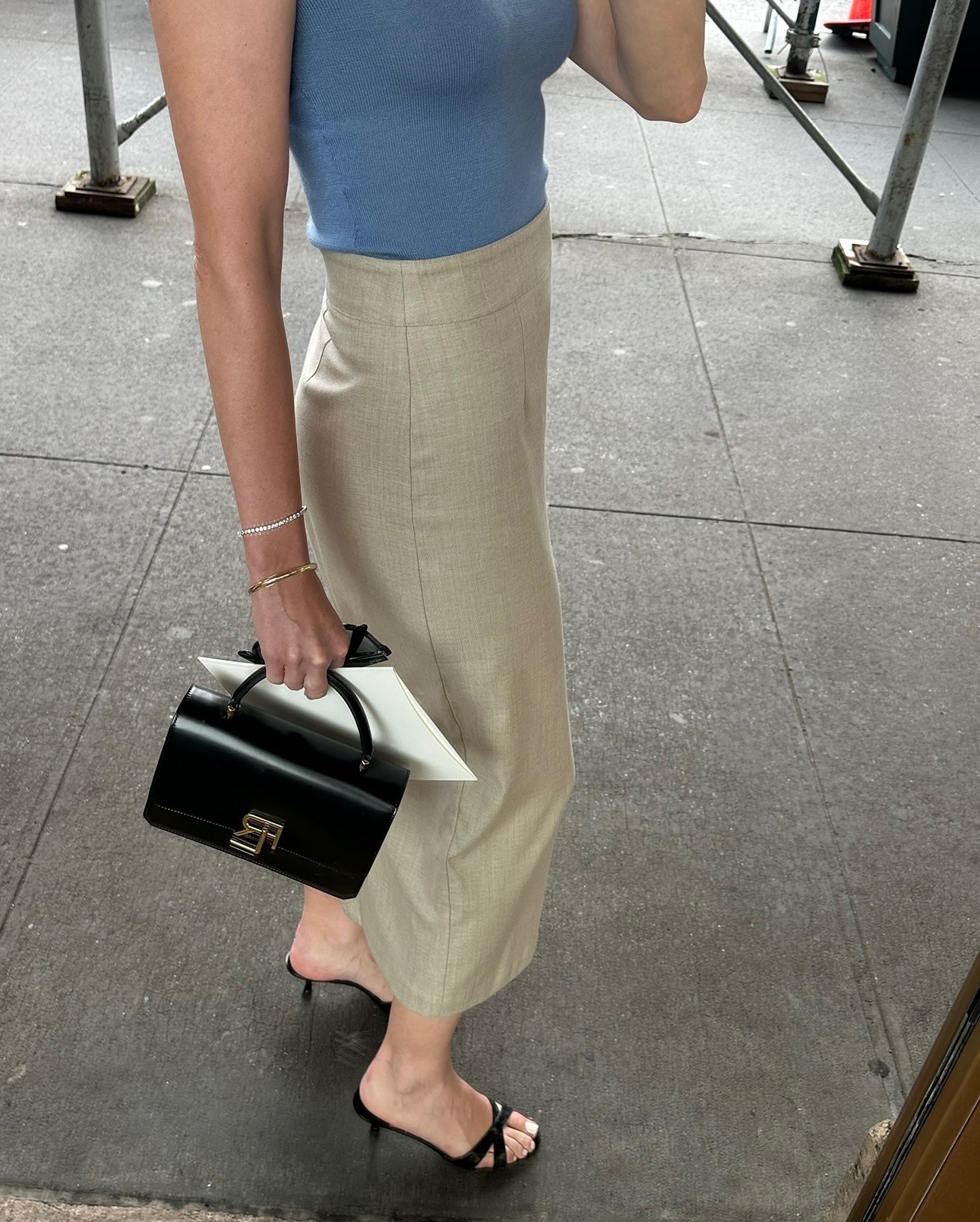 @kristenmarienichols wearing a blue top with a khaki skirt and black sandals.
