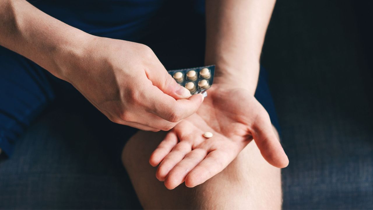 Woman holding packet of tablets, representing HRT, open on her lap