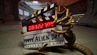 A costume Alien claw holds a director's board that says