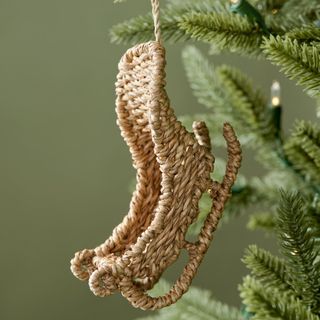 Rattan Sleigh Ornament against a green background.