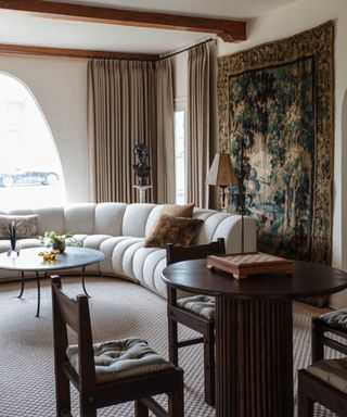 Neutral living room with large scenic wall hanging and white curved sofa