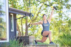 Woman following a bodyweight workout plan using TRX straps