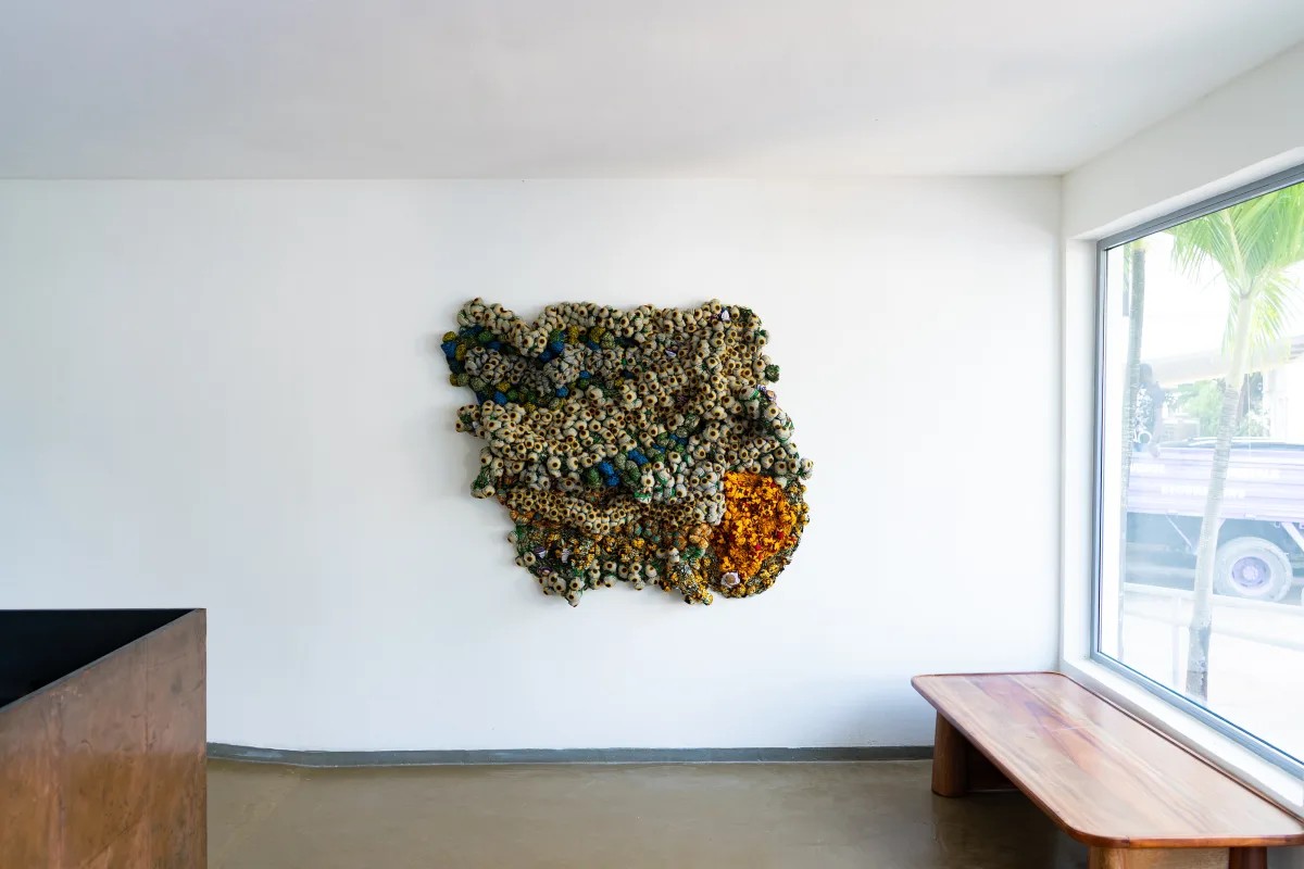 An installation view of a textile sculpture exhibition in a naturally lit gallery space.