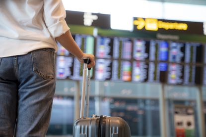 A woman at the airport looking at the departure board.