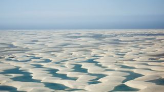 White sand dunes formed by wind and water surround the blue lagoons in the Lencóis Maranhenses National Park