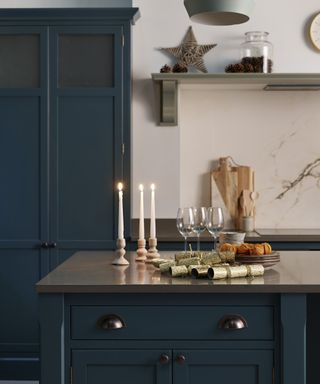 Kitchen Christmas decor ideas with candles, wine and fruit on the island, and a wicker star on the shelf