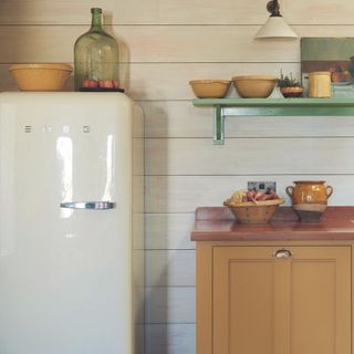 coastal kitchen with yellow cabinet green wall shelf and smeg fridge