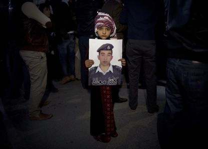 A Jordanian child holds photo of pilot