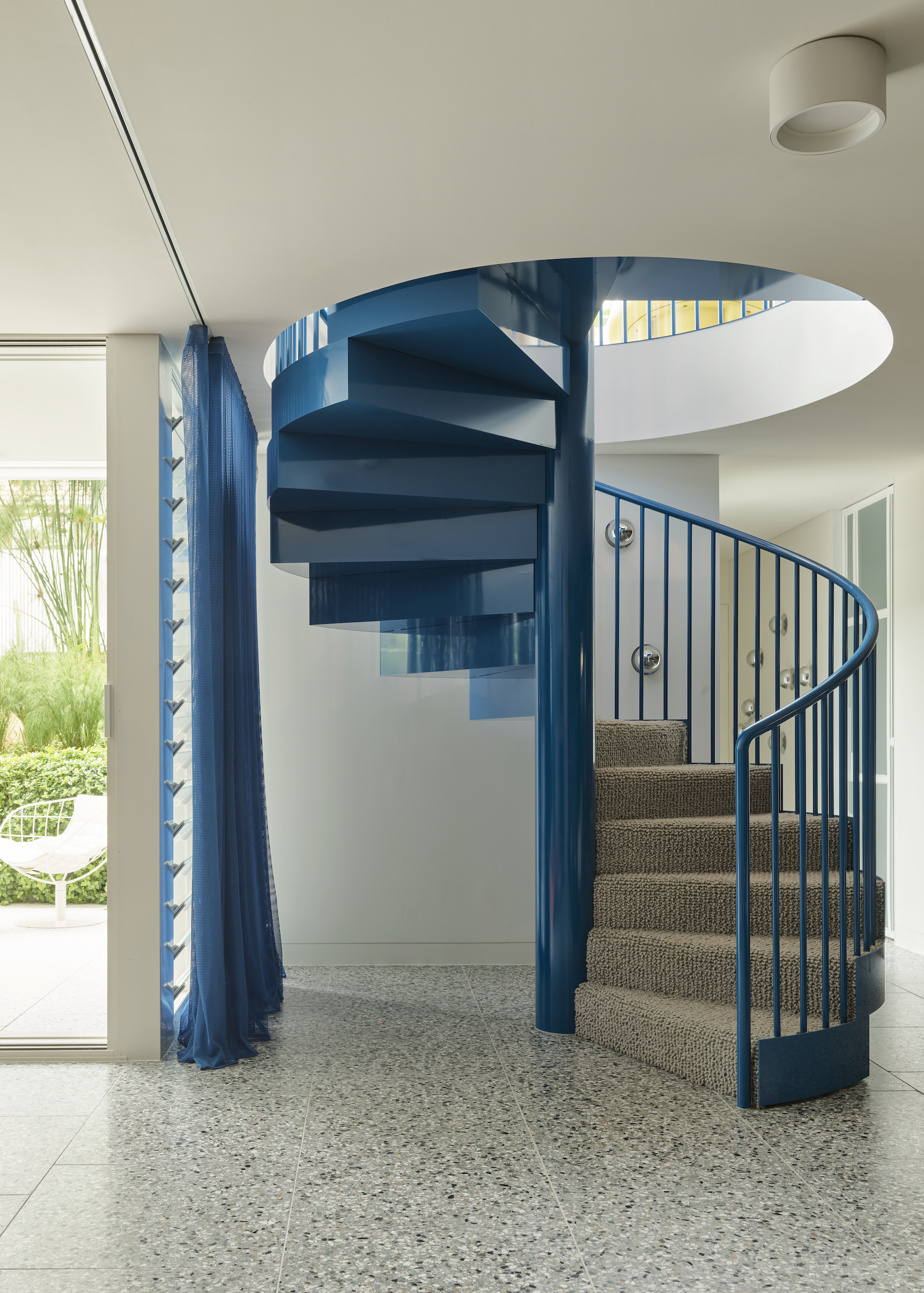 a blue spiral staircase with terrazzo flooring in a home