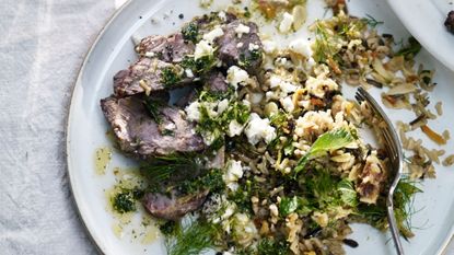 Plate of barbecued lamb and pilaf rice with green leaves