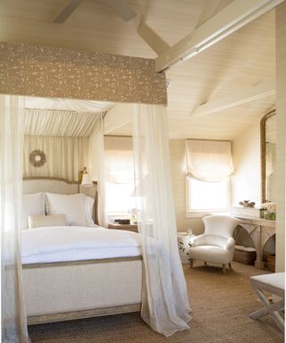 bedroom with vaulted roof and four poster sheer drapes and cream walls
