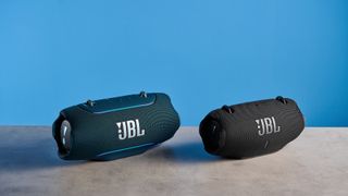 the JBL Xtreme 5 bluetooth speaker in blue shown with the rugged carry strap and buttons