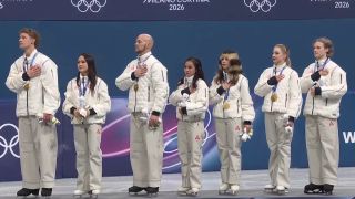 Gold medal USA Figure Skating Team with hands on hearts on podium