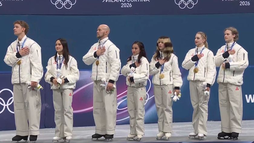 Gold medal USA Figure Skating Team with hands on hearts on podium