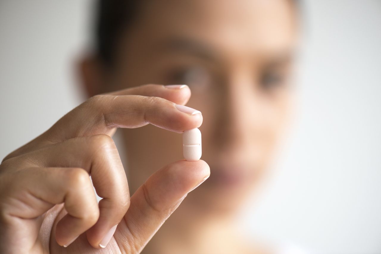 Woman holding medication capsule.