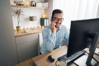 Smiling man on phone in home office