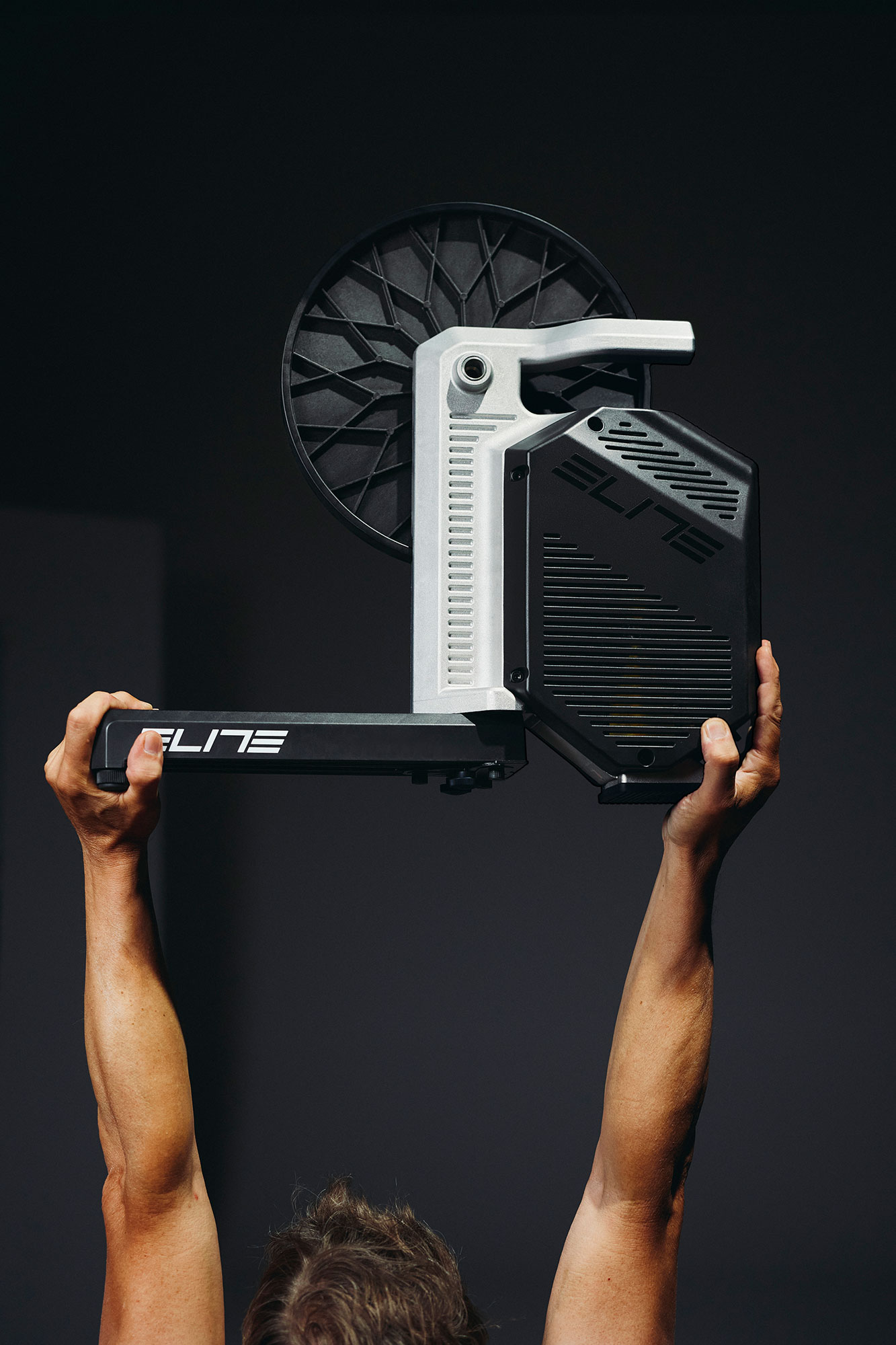 Elite Rivo with Zwift Cog and Click being held aloft by two hands