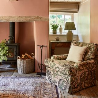 country cottage living room wth fireplace with wood burner, pink walls and traditional armchair