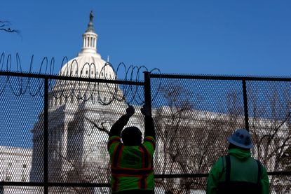 Workers install barbed wire on security fencing surrounding the U.S. Capitol