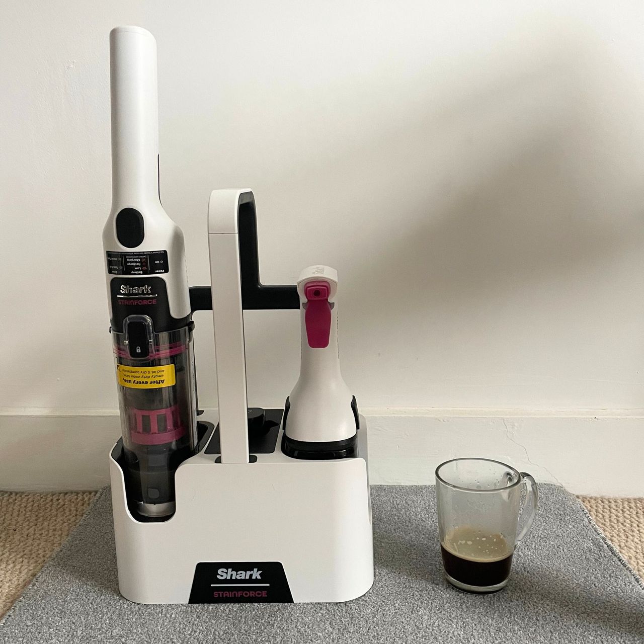 Shark Stainforce Spot Cleaner on a grey carpet sample, next to a cup of coffee