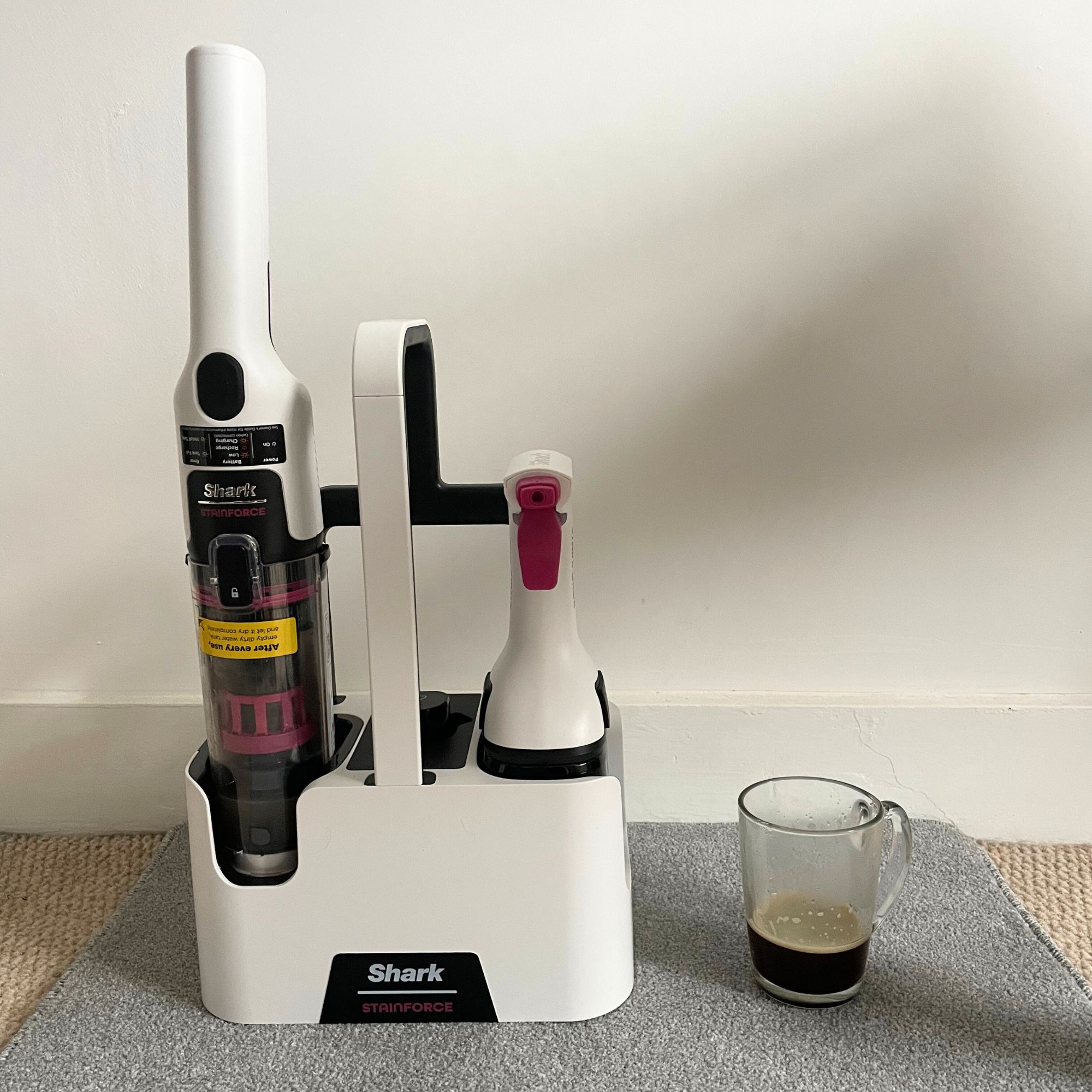 Shark Stainforce Spot Cleaner on a grey carpet sample, next to a cup of coffee