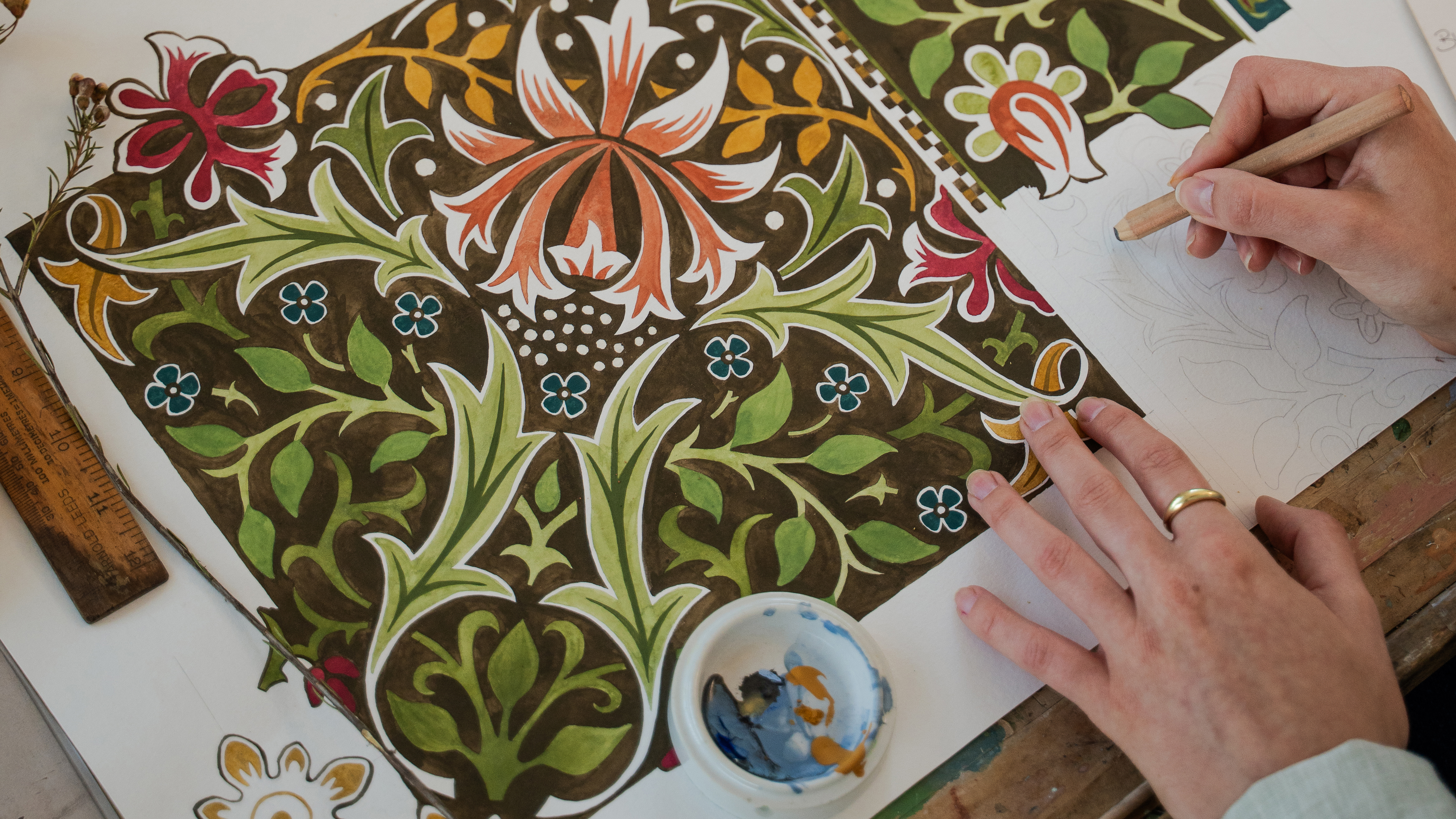 A hand on a pattern of wallpaper, someone is drawing on it