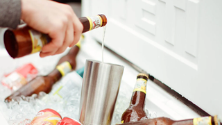 Person pouring beer into cup inside Yeti cooler full of ice