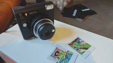 The Instax SQ40 with two images captured by it laying in front