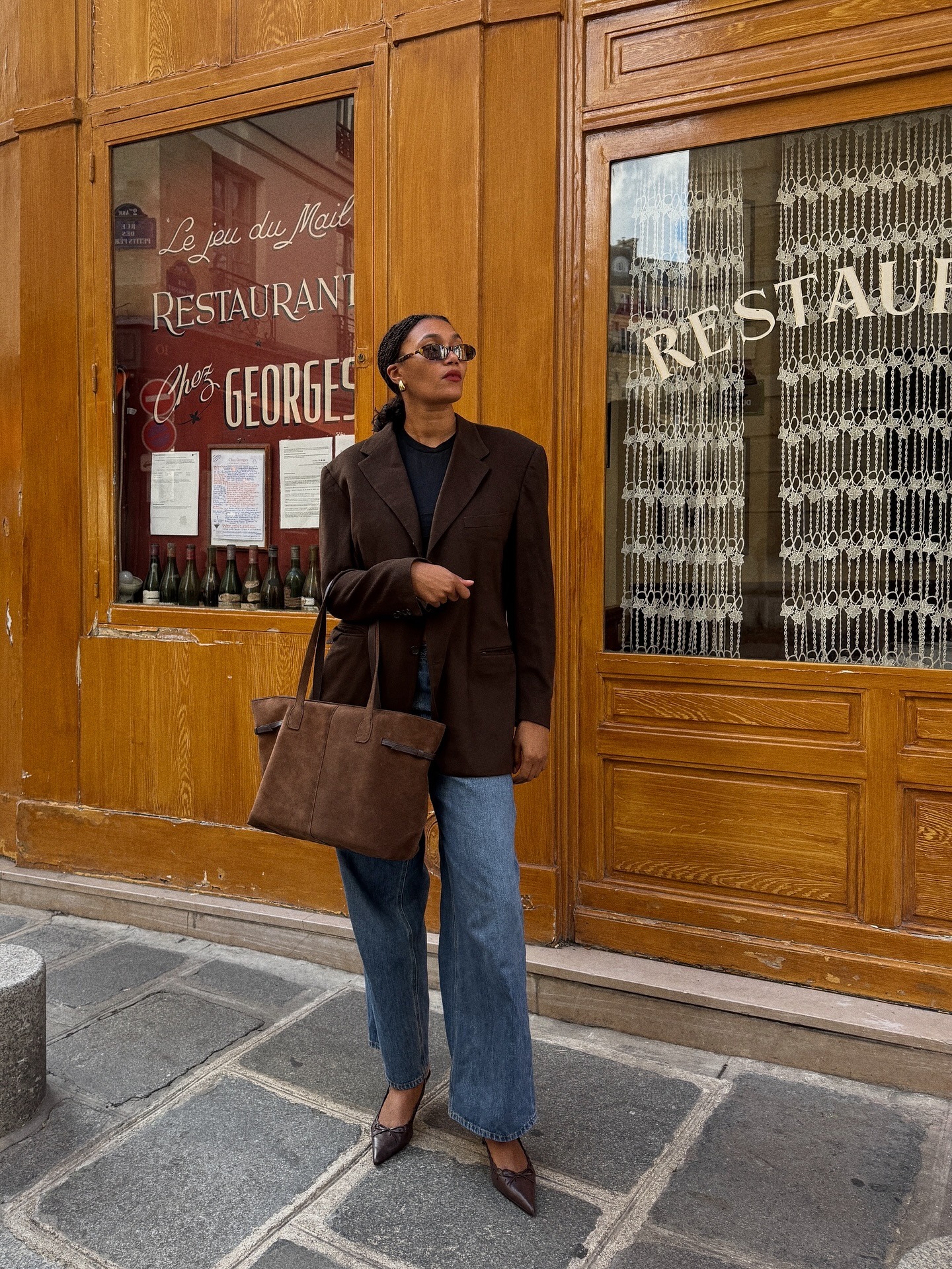 Woman in wide-leg jeans and brown suede blazer.