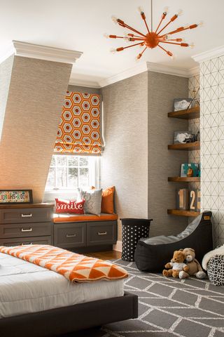 gray and orange teen bedroom with gray textured wallpaper, open shelving, graphic gray rug, orange retro pendant, orange geometric blanket