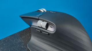 A photo of the Logitech MX Master 3S on a black slate against a blue background.