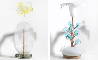 Two side-by-side photos of two pieces from The Glass Calendar collection pictured against a light coloured background. The first piece features clear and yellow glass spheres and the second piece features blue glass spheres and white glass elements