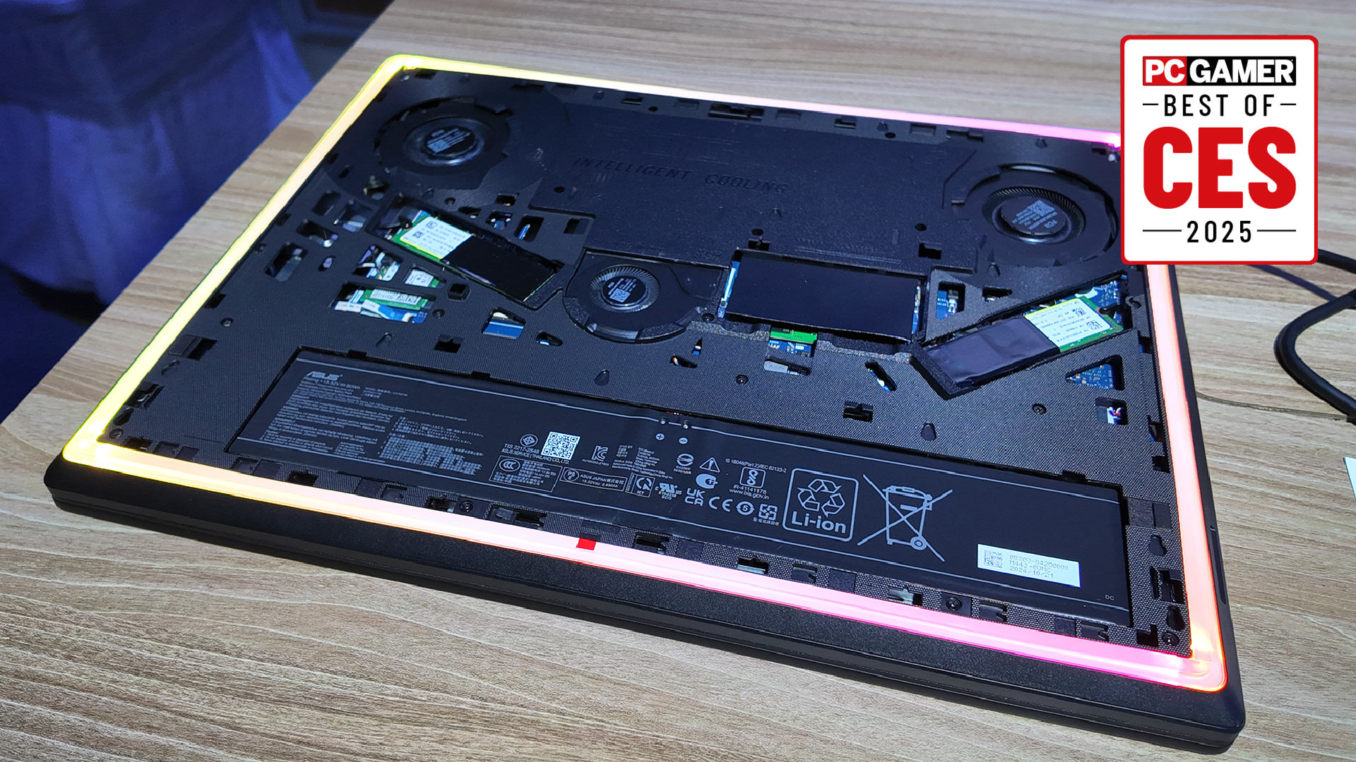 The Asus ROG Strix Scar 18 with the backplate removed, showing the easily upgradeable SSDs mounted diagonally, with the PC Gamer Best of CES 2025 award logo in the top right.