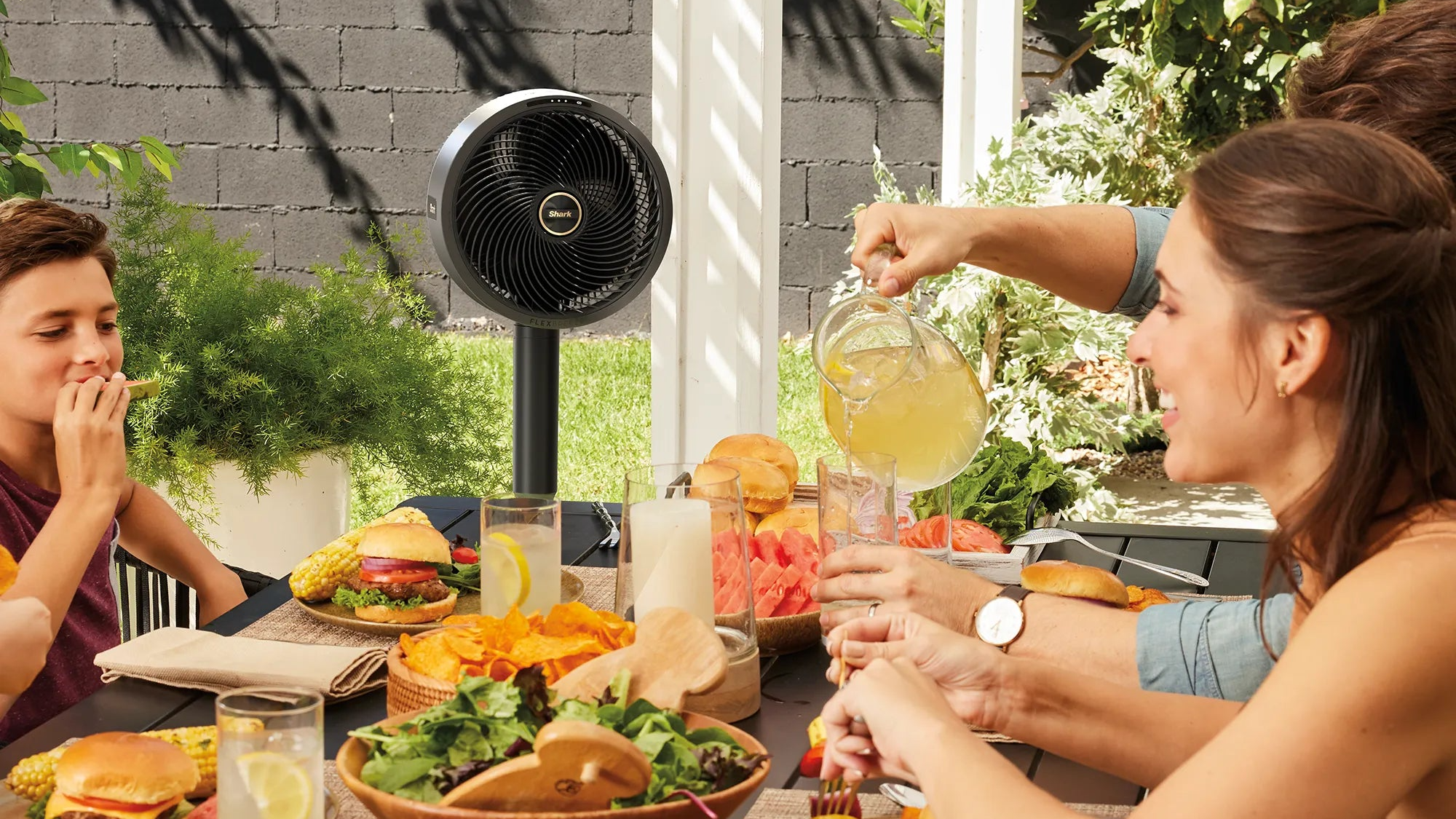 Shark Flexbreeze lifestyle image of family sitting around table with food and fan in the background