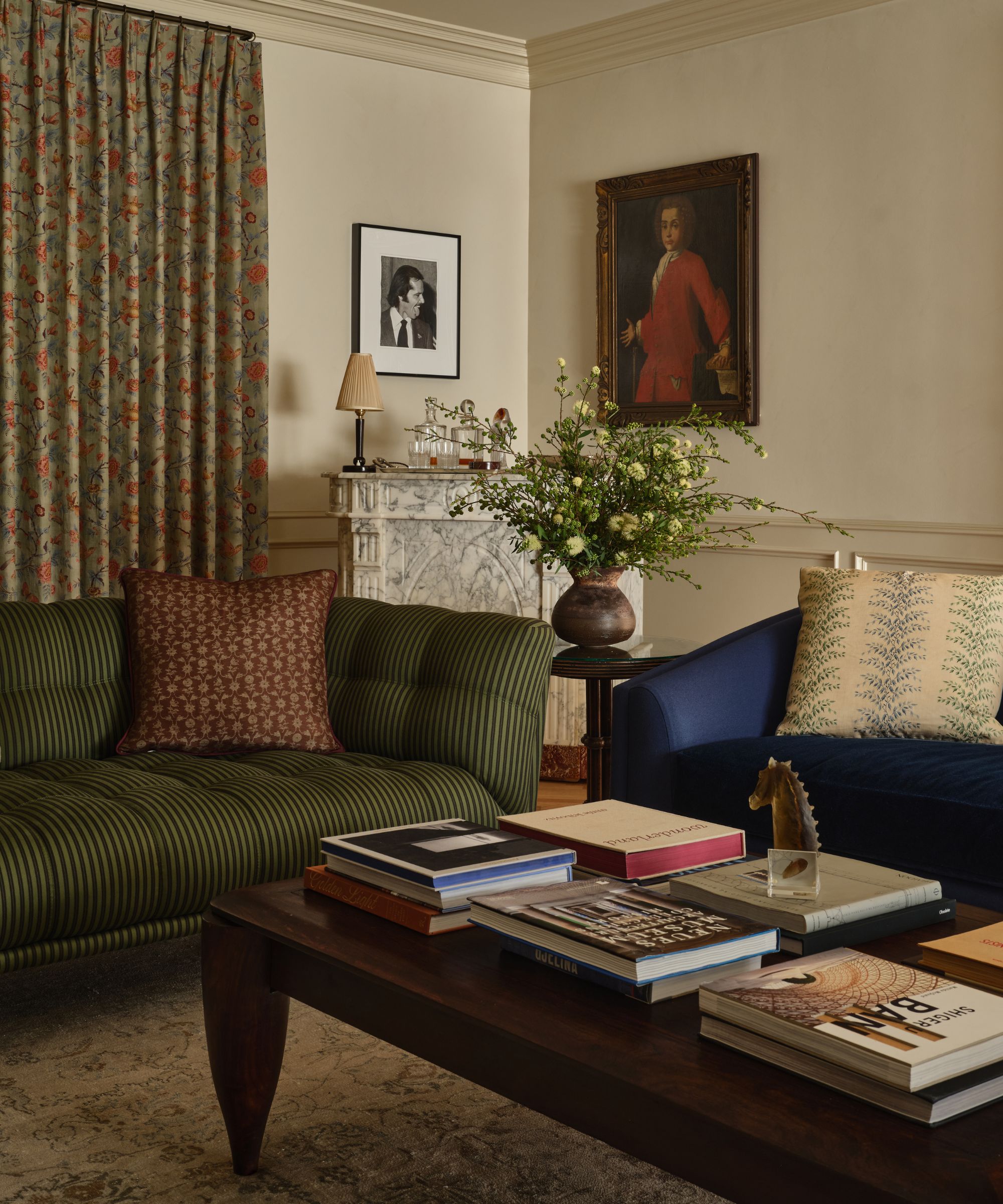 Cozy living room with a navy velvet sofa, a striped olive green sofa, an orange upholstered armchair, and a dark wood coffee table