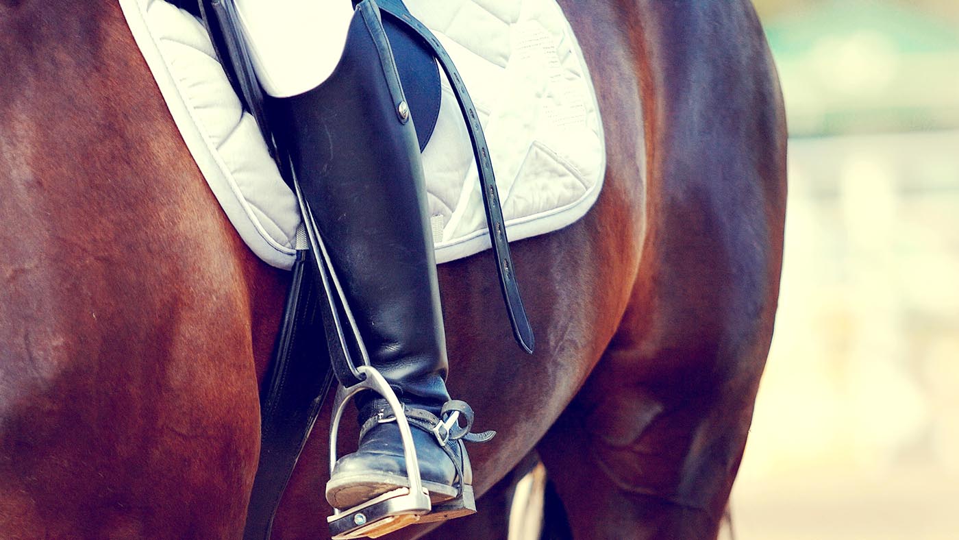 Foot of the athlete in a stirrup astride a horse