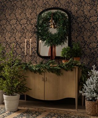 A Christmas wreath hung on a wall mirror