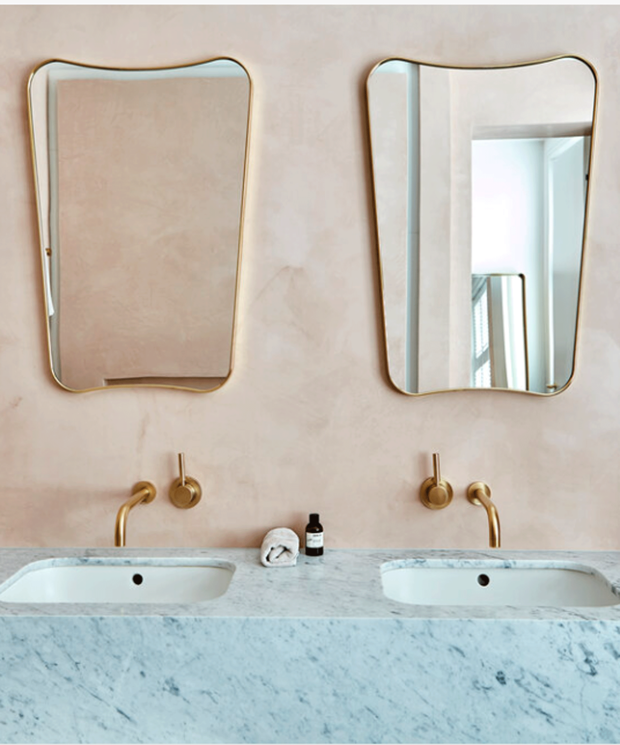 Pink tadelakt wall in bathroom with two mirrors and double sink