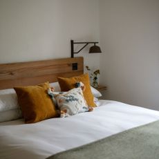 White bedroom with wooden headboard and lamp