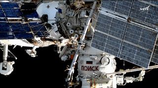 Two Russian cosmonauts work outside of the International Space Station during a spacewalk.