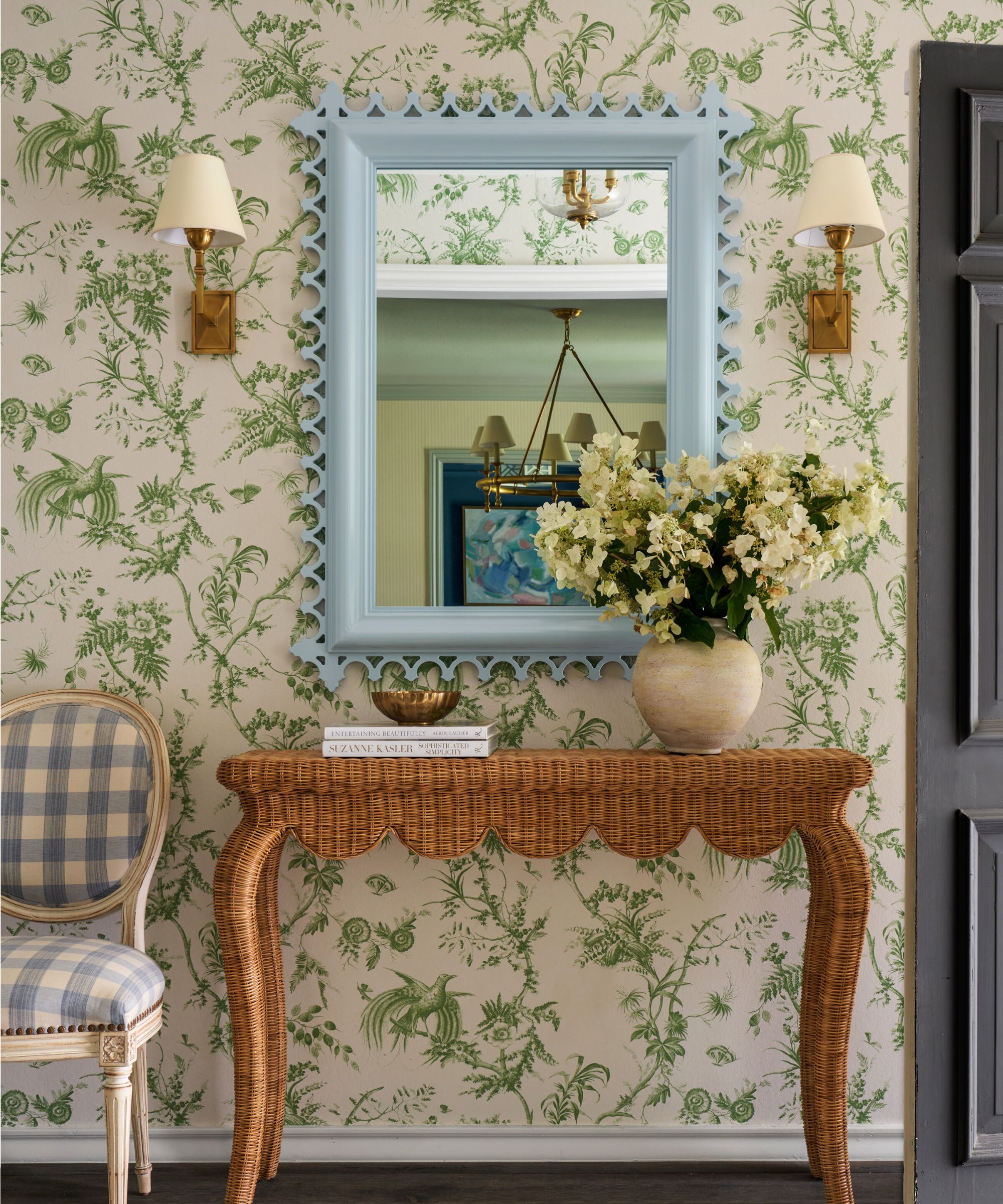 Katie Davis Design hallway with green botanical wallpaper and blue mirror and gingham chair with rattan side table