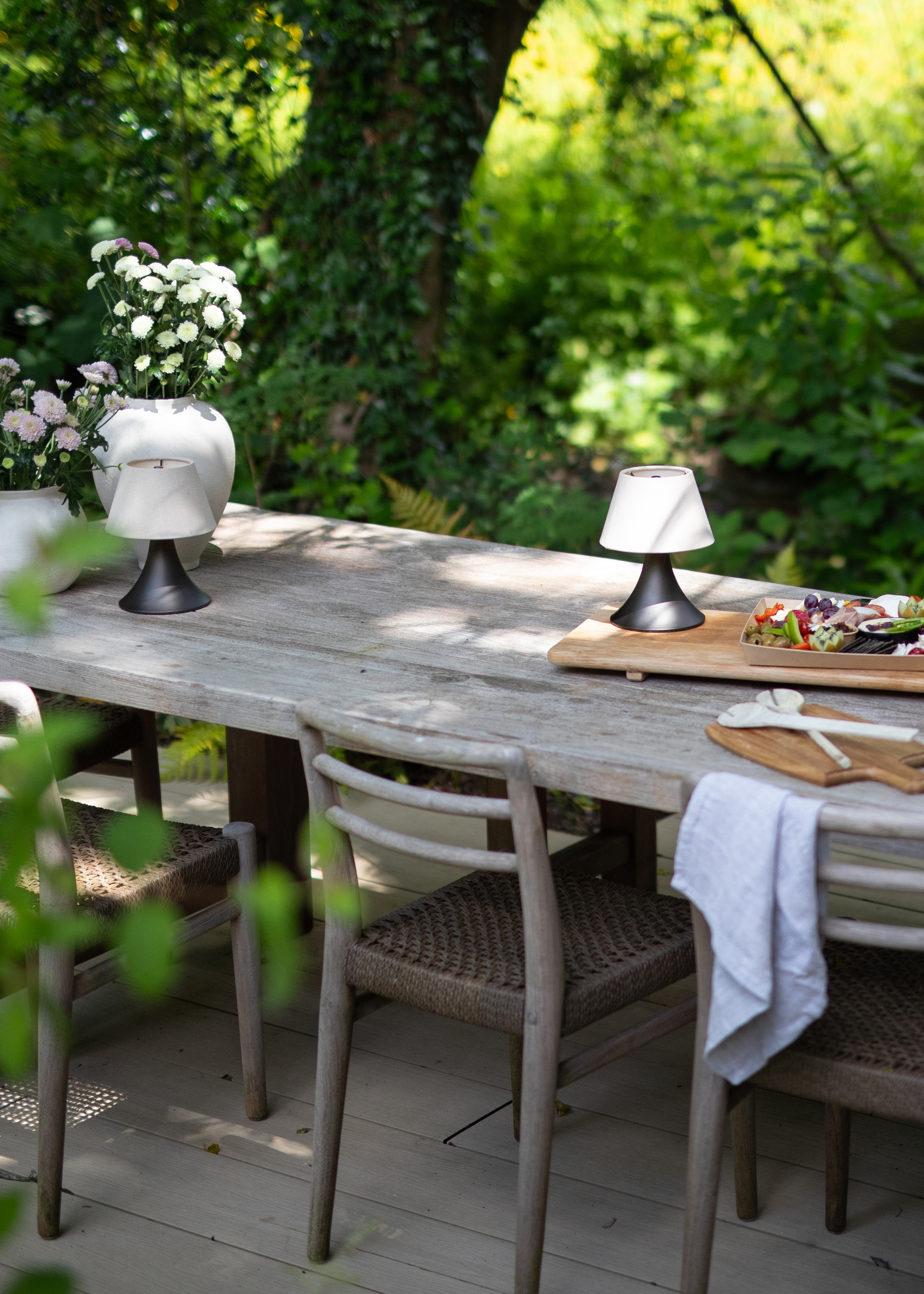 An outdoor dining bench with two portable lamps on the surface